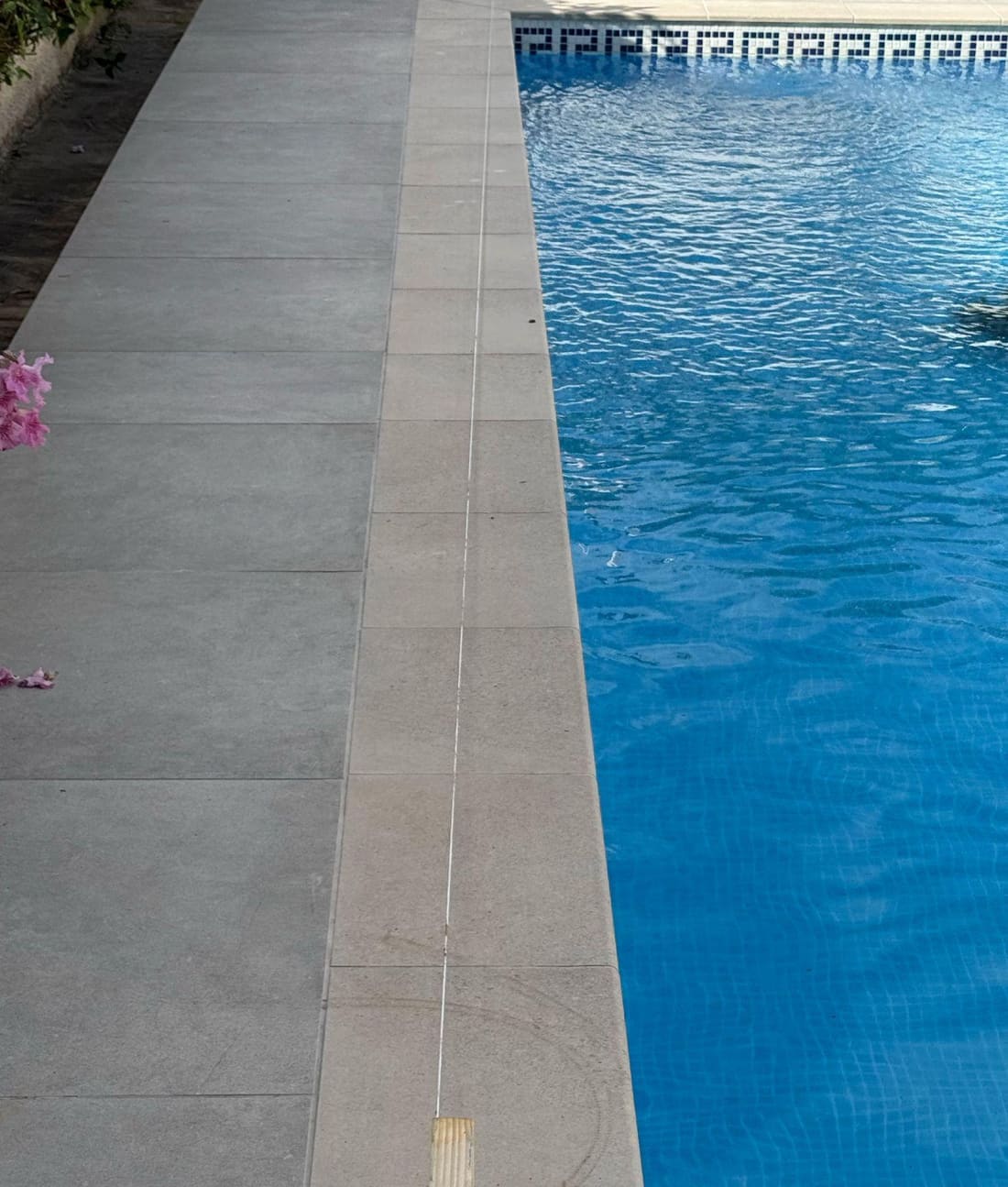 En el extremo opuesto, la línea propuesta (el cordel blanco) llega prácticamente al borde de la piscina — visiblemente fuera de la retícula.